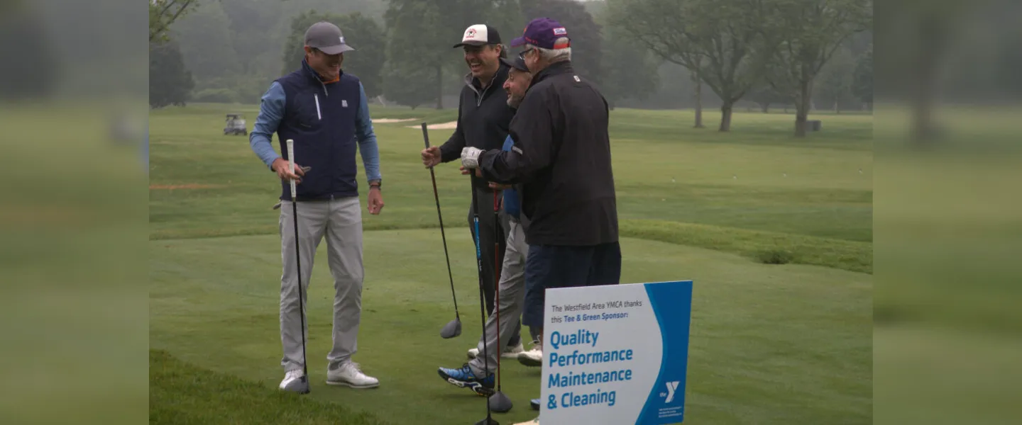 golfers laughing by sponsor sign
