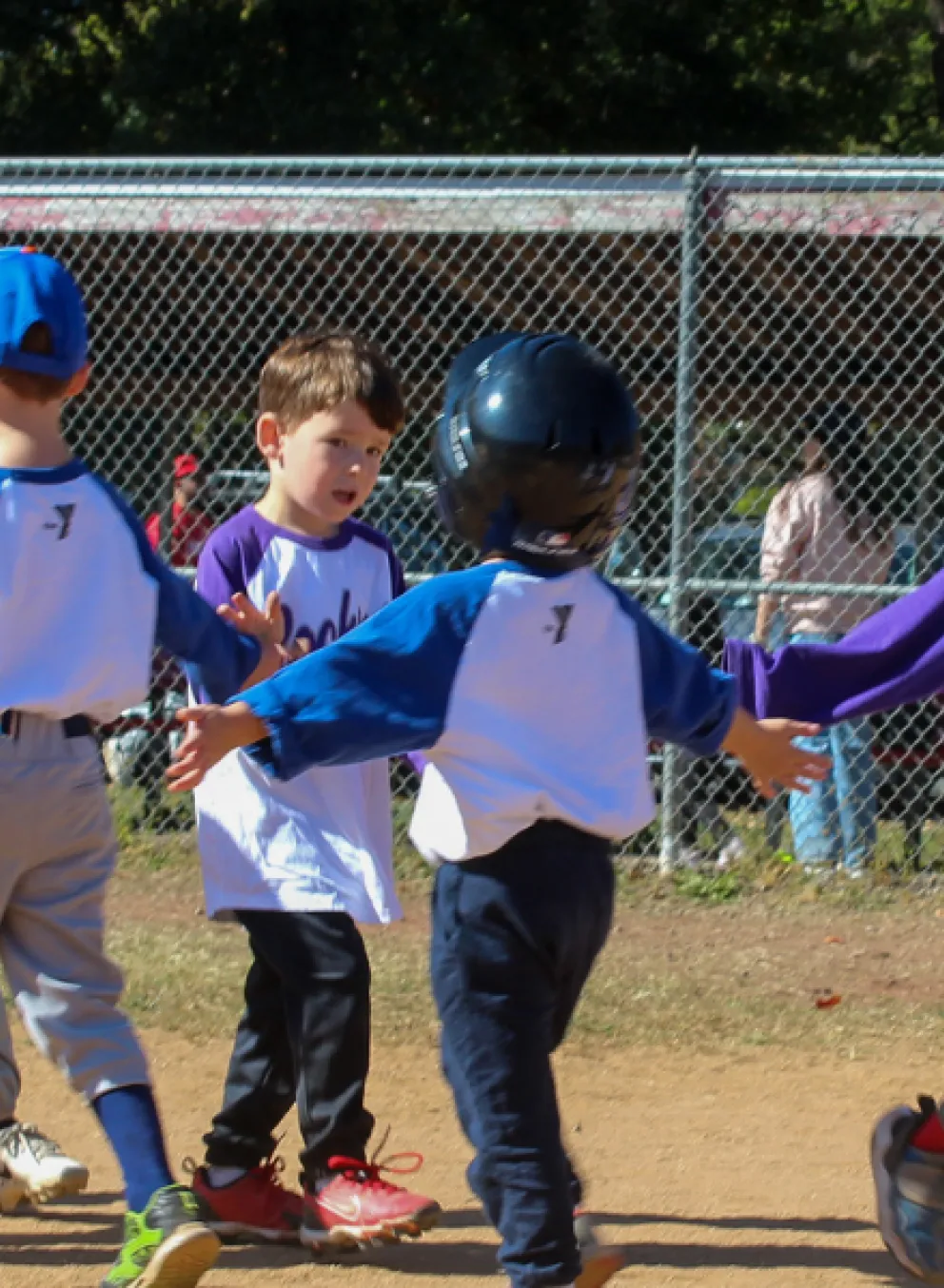 Group of T-Ball players high-five each other after a game.